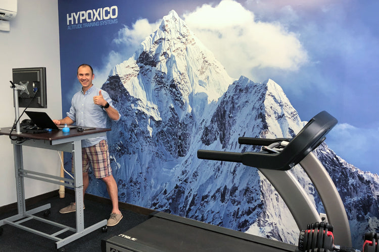Man with laptop and treadmill by mountain mural