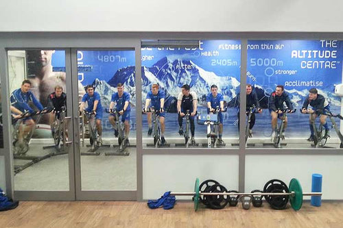 Sports team on stationary bikes inside altitude chamber