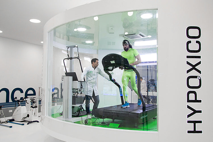 Altitude chamber with athlete on treadmill and scientist monitoring his vitals