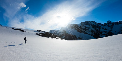 Man trekking through the snow, surrounded by mountains