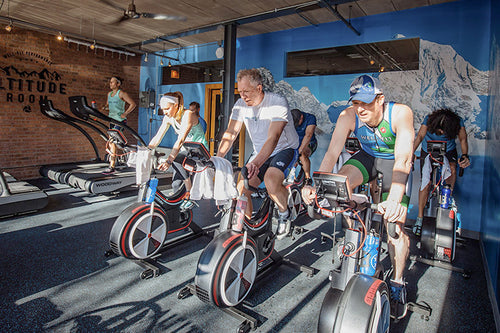 Group of people working out on stationary bikes inside an altitude chamber