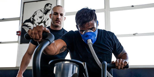 Man exercising on elliptical while wearing a altitude training mask